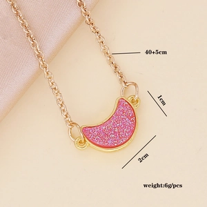 Detail shot of a golden crescent moon necklace with pink glitter inlay and dimensions