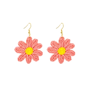 Détail de boucles d'oreilles marguerites roses tissées main avec crochets dorés