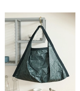 Close-up of dark green wrinkled DuPont paper tote bag with woven strap hanging on a rack