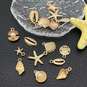 Detailed close-up of golden sea shell and starfish alloy pendants for DIY jewelry making