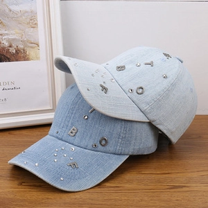 Detailed view of denim baseball caps with crystal rhinestones and metal letter charms