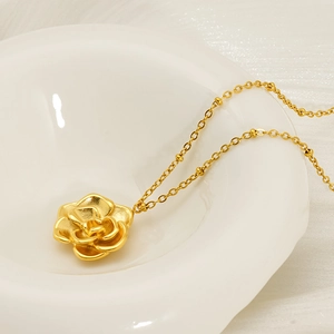 18K gold plated stainless steel rose pendant necklace displayed in a white ceramic bowl