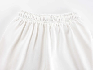 Detail view of the elastic waistband on white straight-leg sports pants with fabric texture