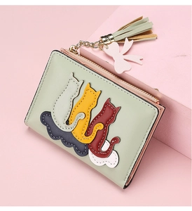 Detailed macro view of mint green leather wallet with colorful cat patterns and gold tassel