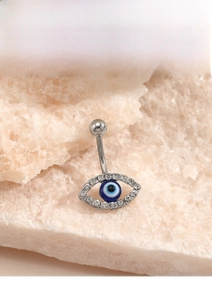 Macro detail of silver stainless steel evil eye belly ring with sparkling blue crystal
