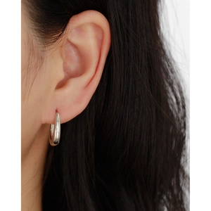 Close-up of minimalist polished S925 sterling silver hoop earring on model's ear