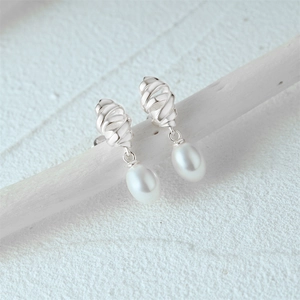 Detail of S925 silver croissant earrings with oval pearls hanging on a white branch