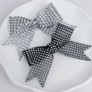 Sparkling rhinestone bow hair clips in silver and black on a white ceramic plate