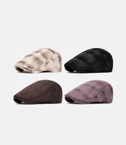 Close-up of four stylish flat caps in various colors including tie-dye and solid textures