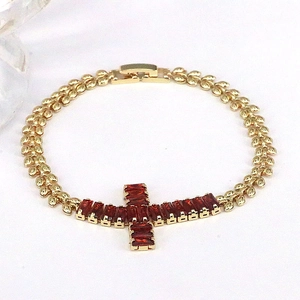 Detail of gold cross bracelet with red zircon inlay and unique leaf-shaped chain links
