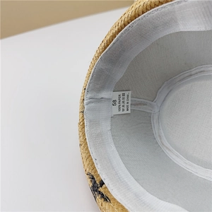Detail view of the straw hat interior featuring the 100% paper material label and sweatband