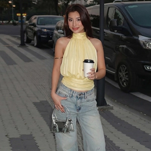 Street style view of a woman wearing a yellow backless halter top and blue jeans