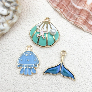 Detail of ocean-themed enamel charms including shell, jellyfish, and mermaid tail