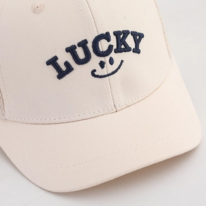 Macro detail of Lucky embroidery and smile pattern on cream mesh baseball cap fabric