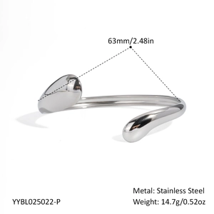 Close-up of wavy stainless steel bangle with polished teardrop ends and 18K gold plating