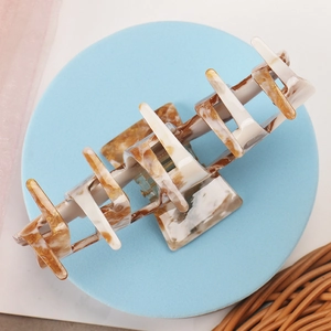Macro detail of large acetate hair claw clip with marble texture on elegant tray