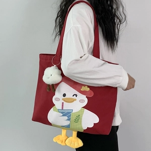 Detail of red canvas tote bag with cute duck print and plush ball pendant charm