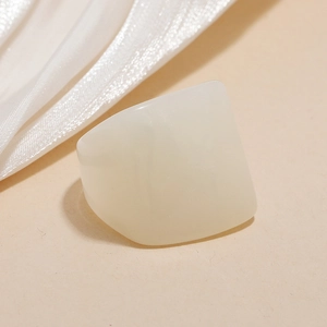 Detail of minimalist cream resin ring on beige background with soft silk fabric textures