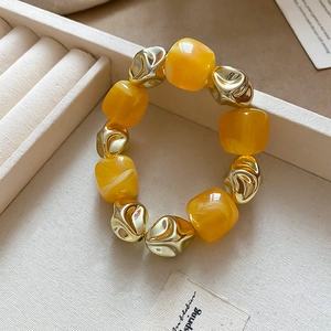 Detailed macro view of yellow resin cubes and irregular gold metal beads in a jewelry box