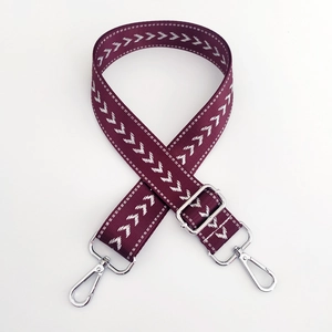 Macro detail of wine red nylon strap with arrow pattern and silver metal hardware