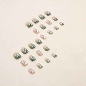 Unghie finte corte quadrate sfumate verde e nude con decorazioni floreali bianche