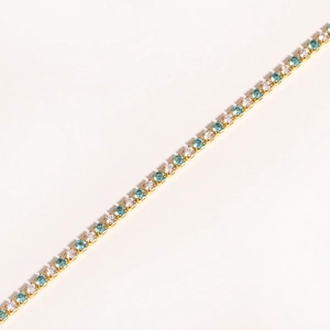 Close-up of gold bracelet with alternating white and blue zircon stones in claw setting