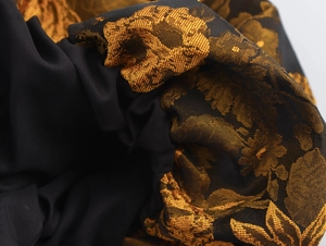 Macro di tessuto jacquard con motivi floreali dorati su base nera elegante