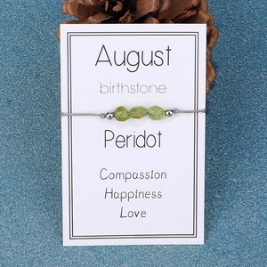 August birthstone bracelet with green peridot chips on a white display card