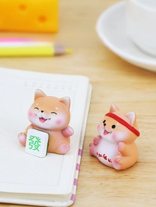 Close-up of two cute Shiba Inu resin figurines with lucky symbols for desk decor