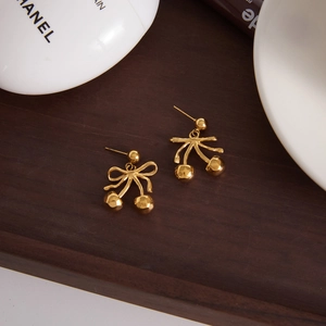 Elegant gold cherry bow earrings crafted in stainless steel on a luxury wooden tray