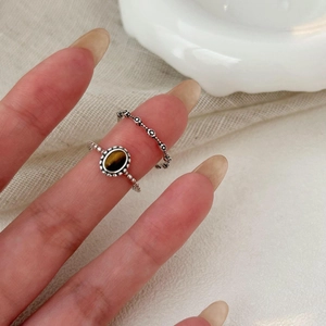 Detail showing stacked vintage S925 silver rings with an oval brown tiger eye stone