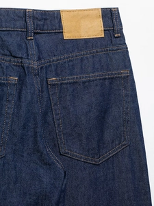 Detalle de pantalones vaqueros azul oscuro de tiro alto con bolsillo trasero y parche de piel