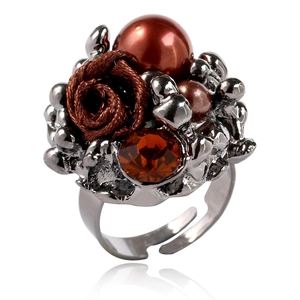 Détail d'une bague rose vintage avec perle marron et gemme sur anneau noir ajustable