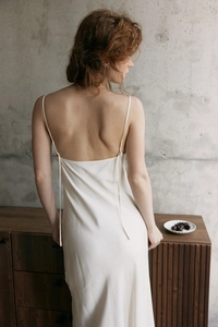 Détail d'une robe longue blanche dos nu en dentelle montrant la texture soyeuse du tissu