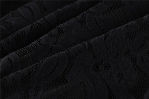 Macro shot of black lace fabric showing intricate hollow floral patterns and textile texture