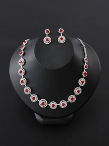 Close-up of silver bridal jewelry set with red stones and crystals on a black mannequin