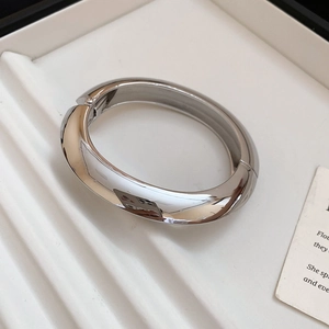 Detailed macro view of silver minimalist oval bangle with hidden hinge and mirror finish