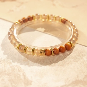 Détail d'un bracelet en bois de santal et agate avec pendentif papillon doré