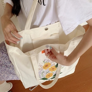 Detail of the magnetic buckle and interior zipper pocket of the floral canvas tote bag