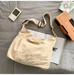 Close-up of beige corduroy tote bag with large front pocket and adjustable shoulder strap