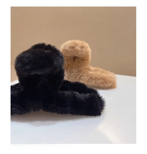 Détail montrant la texture pelucheuse et la fausse fourrure des pinces à cheveux noires et brunes
