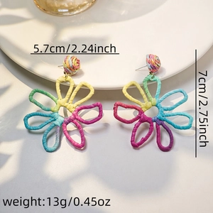 Detail shot showing dimensions of colorful woven raffia flower earrings on a white plate