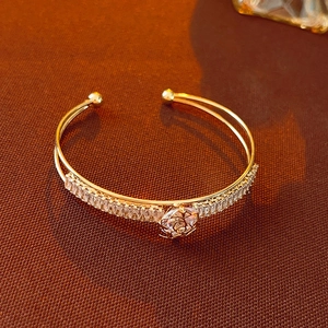 Detail of gold double-layer bangle featuring cubic zirconia row and openwork rose design