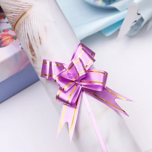 Detail of purple pull bow ribbon with gold edges for festive gift packaging decoration