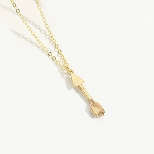 Detailed view of a gold-tone minimalist arrow pendant on a delicate chain necklace
