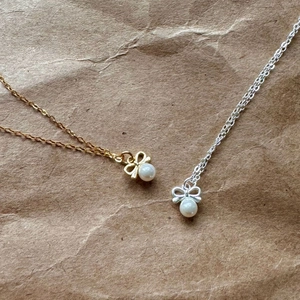 Detailed macro view of gold and silver bow necklaces with round white pearls