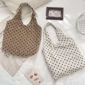Dettaglio delle borse tote a pois marrone e crema su sfondo in tessuto bianco