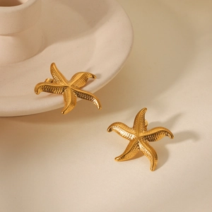 Détail des boucles d'oreilles étoile de mer dorées avec texture métallique grainée