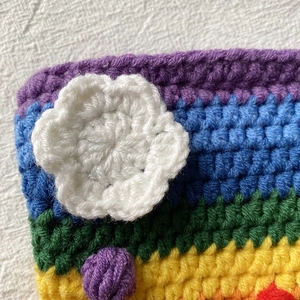 Close-up of rainbow crochet knit bag with handmade 3D floral texture and striped yarn
