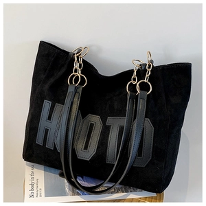 Close-up of black tote bag with large letter print and golden chain shoulder strap